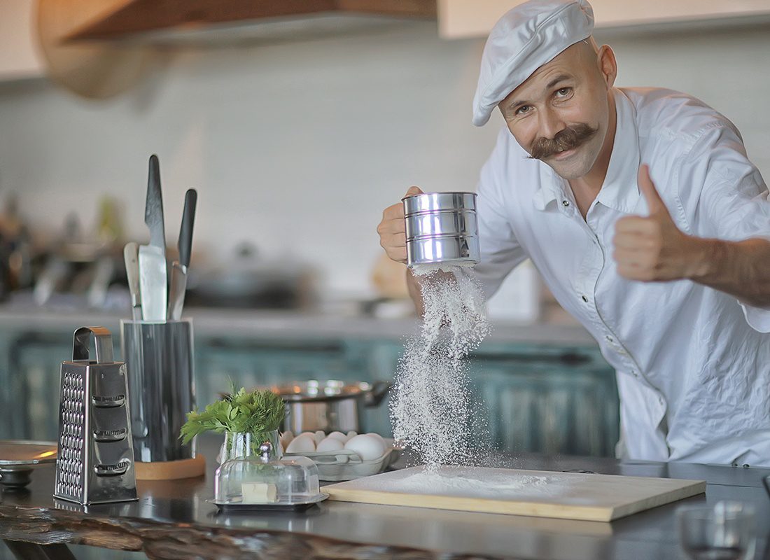 Insurance by Industry - Friendly Chef Gives Thumbs up and Pours Wheat Powder on a Counter